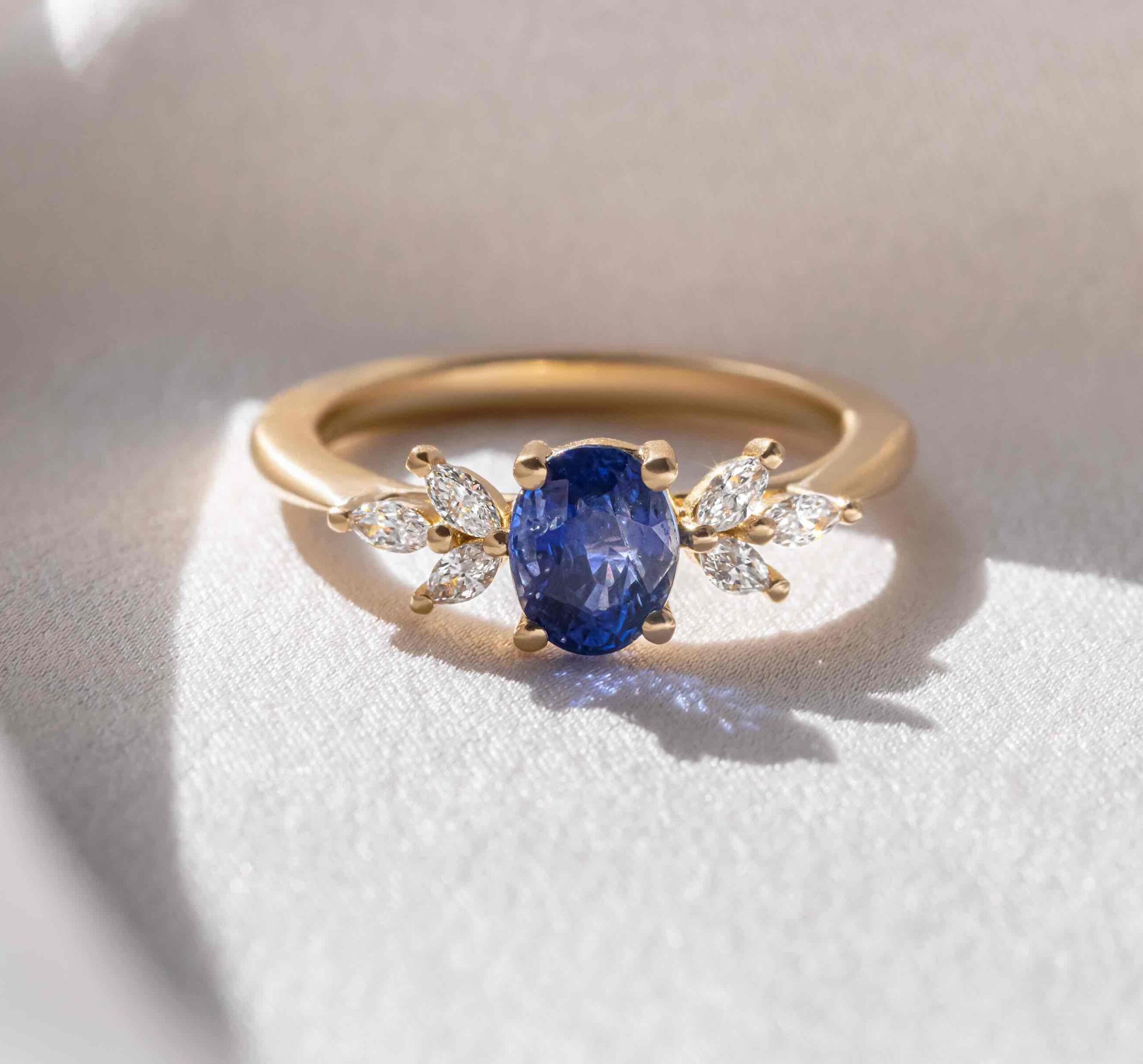 gold engagement ring featuring a blue sapphire gemstone and diamonds for sidestones