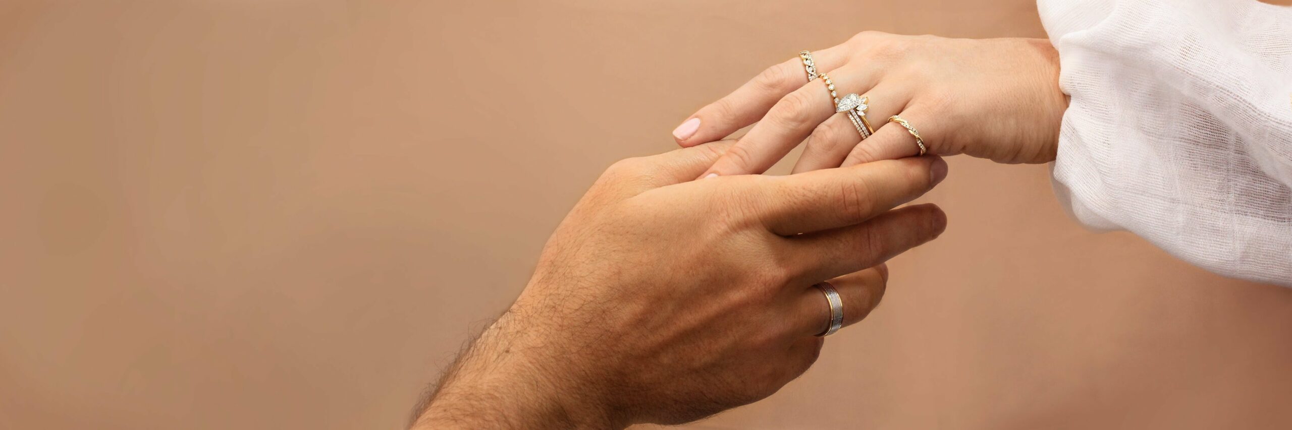 a man's and a woman's hands holding together showing the wedding and engagement rings